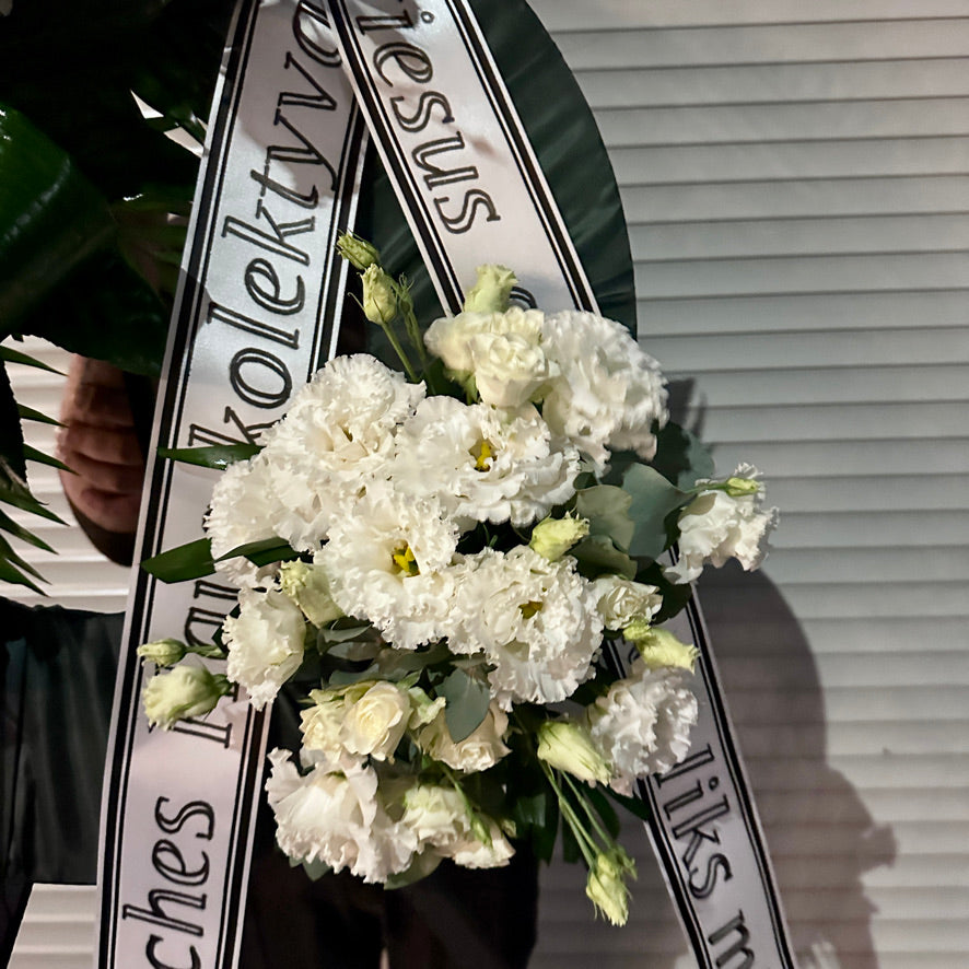 Apvalus, didelis gedulo vainikas - puoštas baltomis kalijomis, karališka balta eustoma, sodria žaluma ir šviesiai žalio eukalipto akentais.